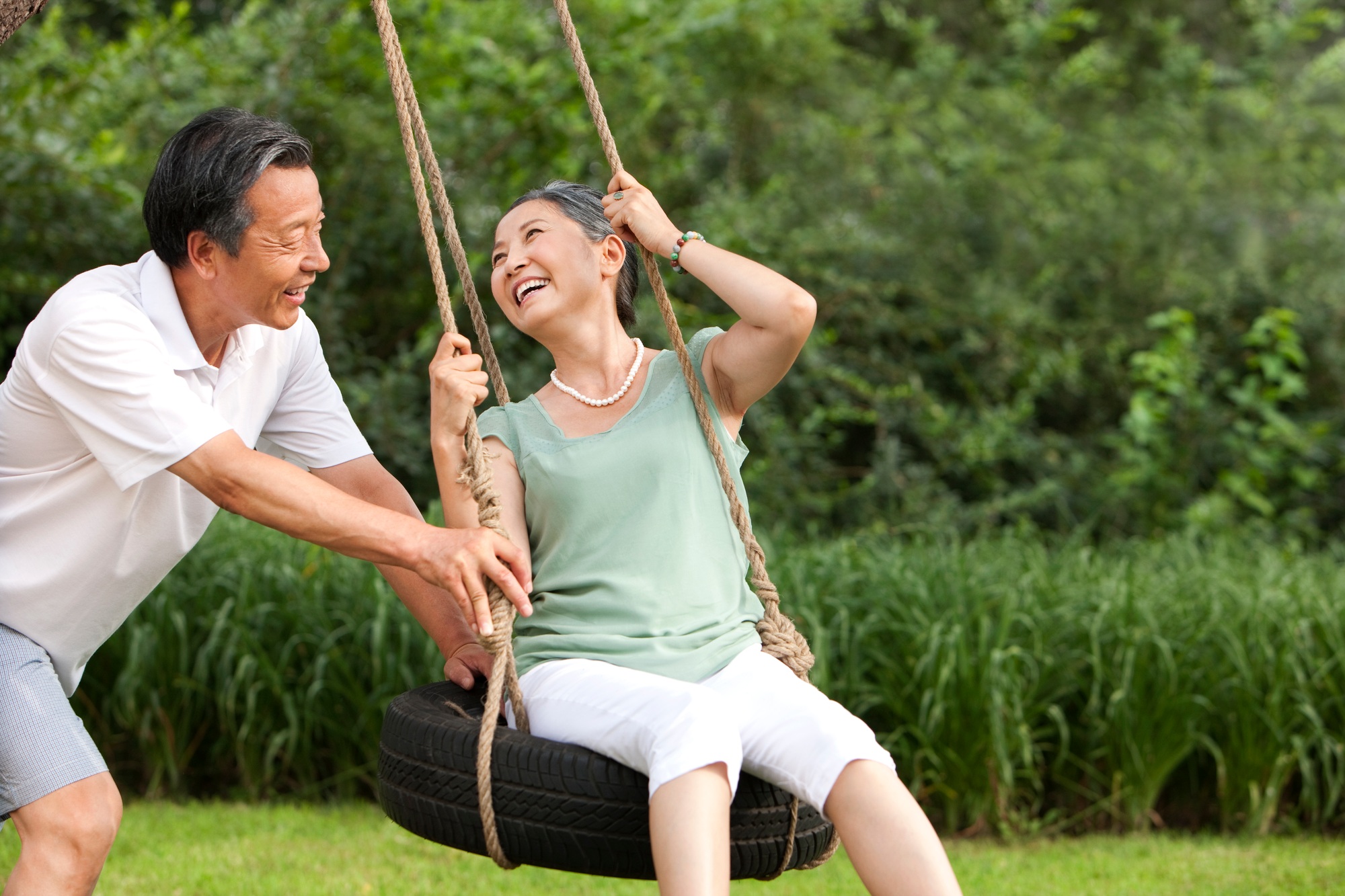Cheerful senior couple playing on a swing